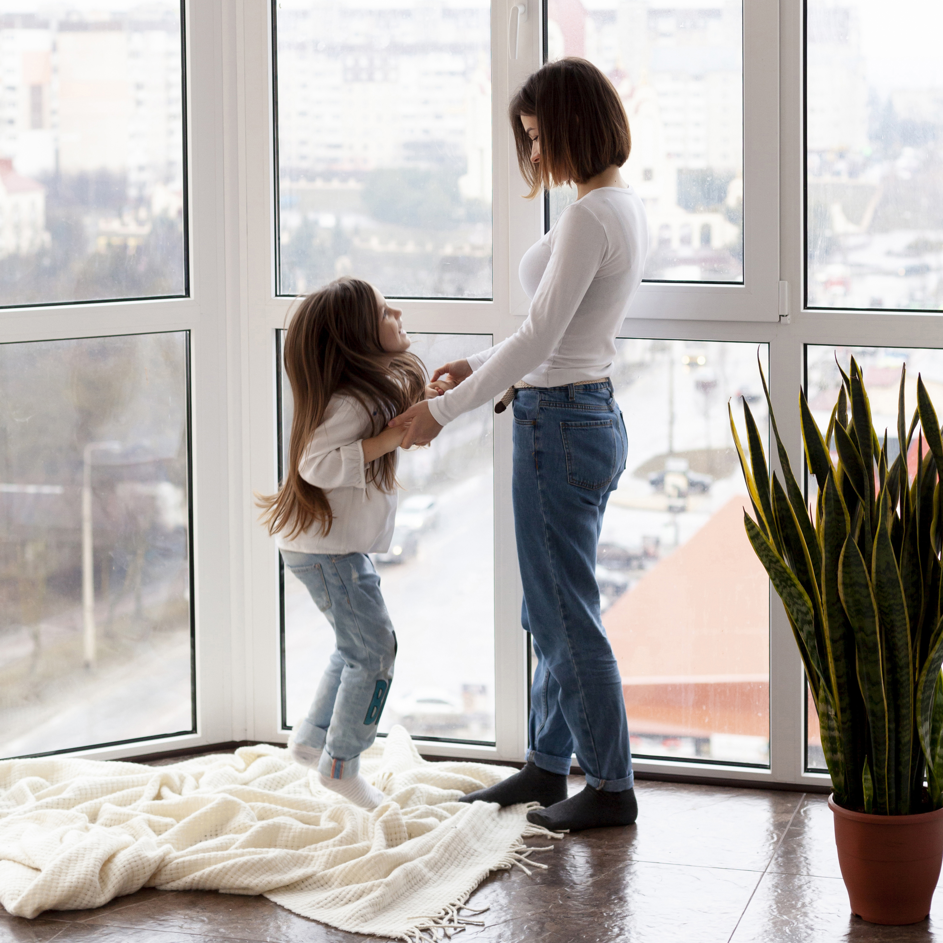 Mãe e filha diante de uma grande janela